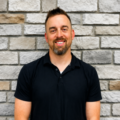 A headshot of a man in front of a stone wall