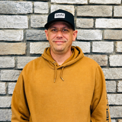 a man in a hoodie in front of a stone wall