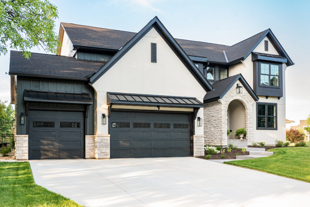 Modern two-story home exterior featuring white thin cut stone veneer accents on the garage pillars and a matching grand stone arch entryway.